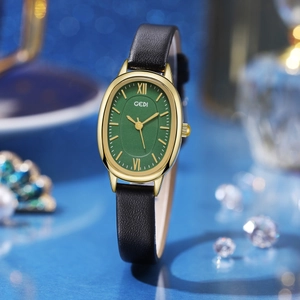 Detailed view of an oval gold watch case with a vintage green dial and black leather strap