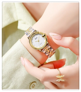 Close-up of elegant gold and silver women's watch with brushed dial on wrist