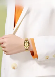 Detail einer eleganten goldenen Tonneau-Uhr am Handgelenk mit minimalistischem Zifferblatt