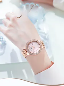 Close-up of rose gold watch with rhinestone bezel, pink dial, and date window