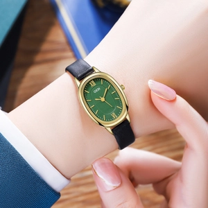 Close-up of GEDI vintage oval watch with green dial and black leather strap on wrist
