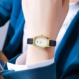 Close-up of GEDI oval gold watch with white dial and black leather strap on female wrist
