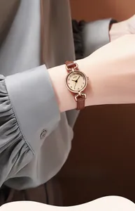 Close-up of minimalist rose gold watch with brown leather strap worn on wrist
