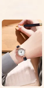 Macro shot of small rose gold quartz watch with black leather strap and round dial