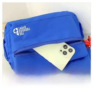 Dettaglio della tasca anteriore con zip dello zaino blu che mostra lo spazio per smartphone