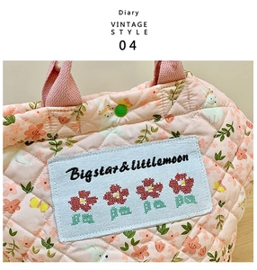 Details einer gesteppten Handtasche mit Blumenmuster, Hasenstickerei und grünem Druckknopf