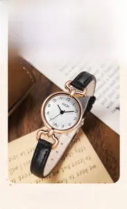 Retro quartz watch with black leather strap and rose gold case on vintage stationery