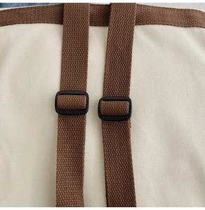 Detail of adjustable brown woven straps and black buckles on cream canvas kid backpack
