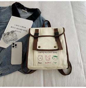 Detail of canvas backpack featuring bear rabbit and tiger prints with metal button pocket