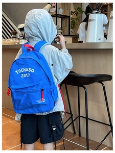Zaino blu per bambini con dettagli rossi, vista laterale in un ambiente da caffetteria