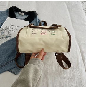 Detailed view of canvas backpack bottom with cute animal prints and brown trim finish
