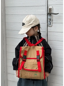 Detail of canvas kids backpack with red trim and cute cartoon animal prints on white background