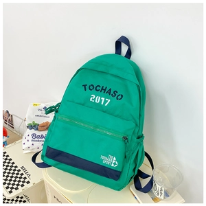 Dettaglio dello zaino verde per bambini con scritte TOCHASO blu e logo sulla tasca anteriore