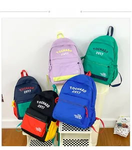 Natura morta di cinque zaini colorati per bambini in nylon con scritte sportive e manici