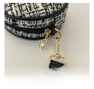 Detailed macro view of black and white tweed fabric with floral gold metal zipper puller