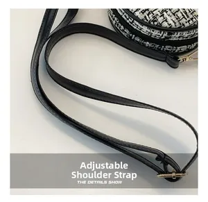 Detail of adjustable black leather shoulder strap and metal buckle on tweed mini round bag