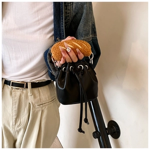 Detail of a black PU leather bucket bag featuring a brown faux fur croissant handle