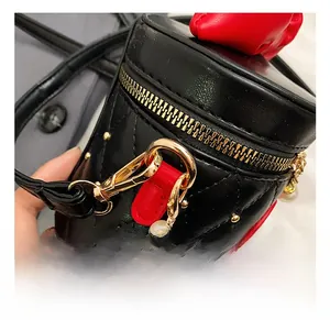 Detail view of black quilted mini bag featuring pearl chain strap and gold metal hook