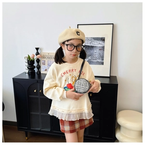 Detail of a girl outfit with a cherry pie sweatshirt and tweed round crossbody bag