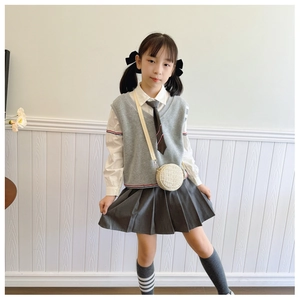Detail of a child in school uniform wearing a stylish small round woven shoulder bag