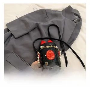 Close-up of black quilted bucket bag with pearl chain handle and red bow detail