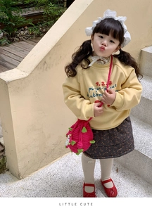 Détail du sweat jaune avec jupe à fleurs et sac bandoulière crochet fruit du dragon rouge