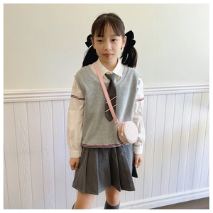 Pink round woven crossbody bag styled with a grey and white girls school uniform