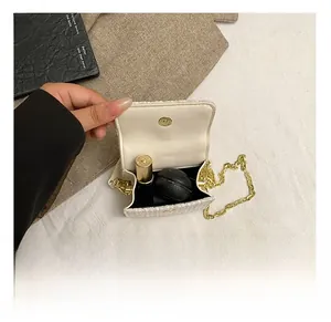 Macro view of the cream tweed handbag interior showing gold chain and small capacity