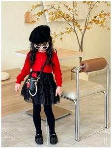 Detailed view of girls' red knit cardigan, black tulle skirt, and pearl chain crossbody bag