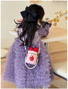 Pink bucket bag for girls featuring red bow detail and pearl chain on a layered dress