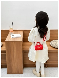 Kleinkind trägt eine rote gesteppte Zylindertasche in einem minimalistischen Café
