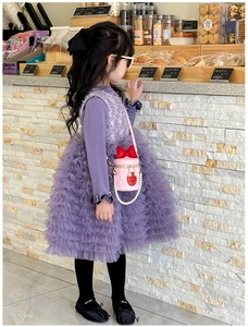 Close-up of pink quilted cylindrical bag with red bow and pearl chain for girls