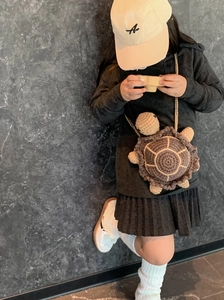 Detail of hand-knitted turtle crossbody bag for kids featuring a cute shell design