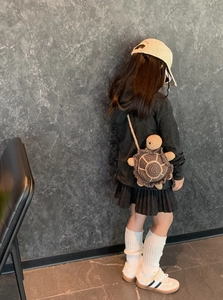 Detail showing the hand-crocheted turtle shape crossbody bag on a child model