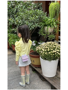 Rear view of girl wearing purple tweed bow crossbody bag with silver sequin tassel boots