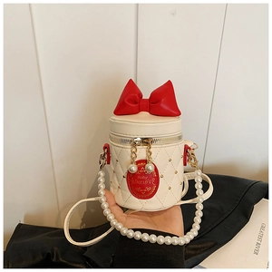 Detail of cream bucket bag with red bow, quilted pattern, and faux pearl handle