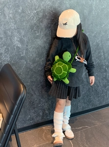 Detailed view of hand-crocheted green turtle crossbody bag on a child model with shoulder strap