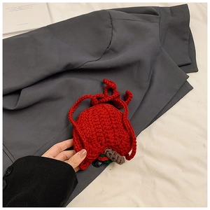 Detail of handmade crochet red apple bag featuring green leaf and knit strap for kids