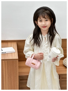 Detail einer rosa gesteppten Kinder-Zylindertasche mit Golddekor getragen von einem Kind