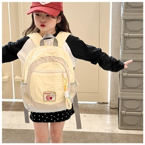 Detail view of yellow children's backpack with gray straps on a young model's back