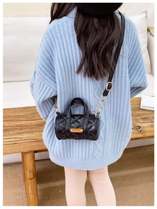 Schwarze gesteppte Zylindertasche für Kinder am Model mit blauem Strickpullover