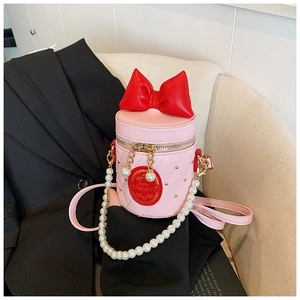 Detailed shot of pink quilted bucket bag with red bow, pearl handle on black blazer