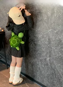 Detailed view of hand-crocheted green turtle crossbody bag worn by a child model