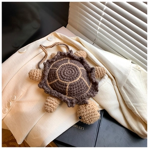 Detail of handmade crochet turtle mini bag placed on a white blazer with a cozy vibe