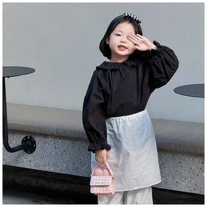 Pink tweed mini handbag with heart hardware held by a young girl in fashionable attire