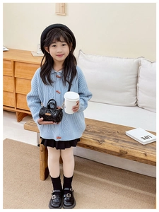 Kleinkinder-Styling mit einer schwarzen gesteppten Mini-Tasche und blauer Strickjacke