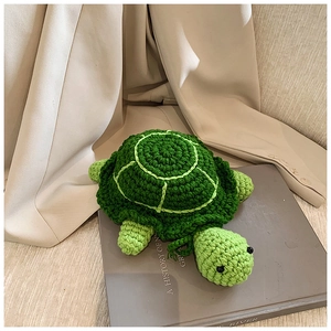 Detailed knit texture of green crochet turtle coin purse on aesthetic book background