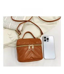 Detailed top view of brown quilted mini box bag with gold zippers and detachable strap