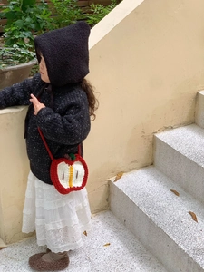 Outdoor lifestyle shot of a cute handmade red apple crochet crossbody bag for kids