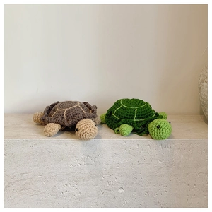 Detail of two handmade crochet turtle bags with visible knitted textures and round shapes
